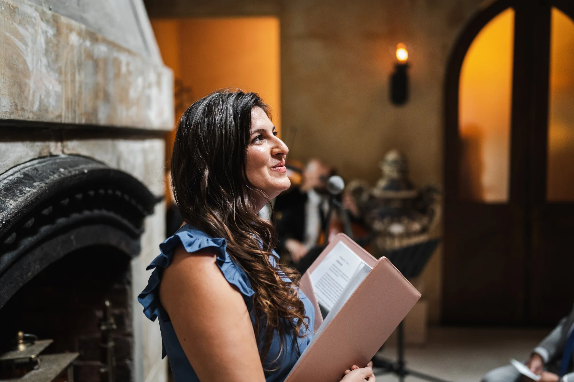 Parisa holding her ceremony book and looking upward at a wedding venue